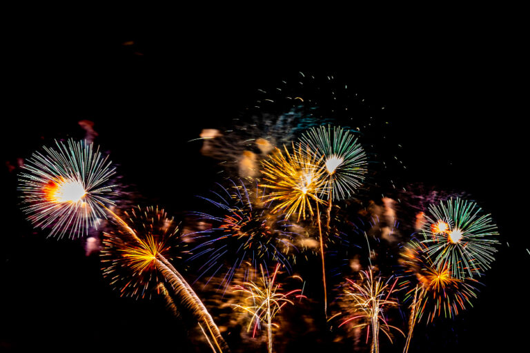 Feu d'artifice multicolore en gerbes dorées, vertes et bleues dans un ciel noir