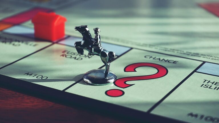 Pion cavalier en métal posé sur la case Chance d'un plateau de Monopoly, avec une maison rouge en arrière-plan