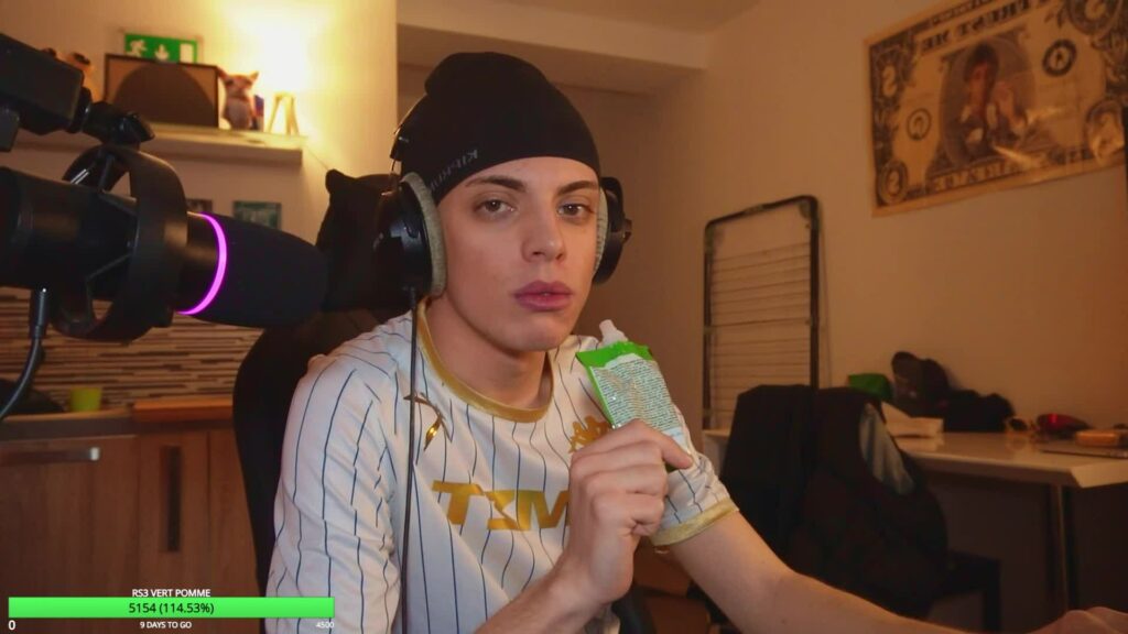 Le streamer Anyme023 en bonnet noir et casque audio, face à son micro, pendant un live dans sa chambre